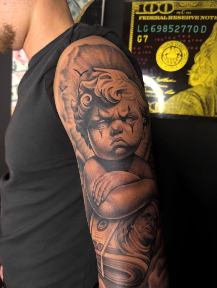 Detailed black and grey cherub tattoo by Jinks